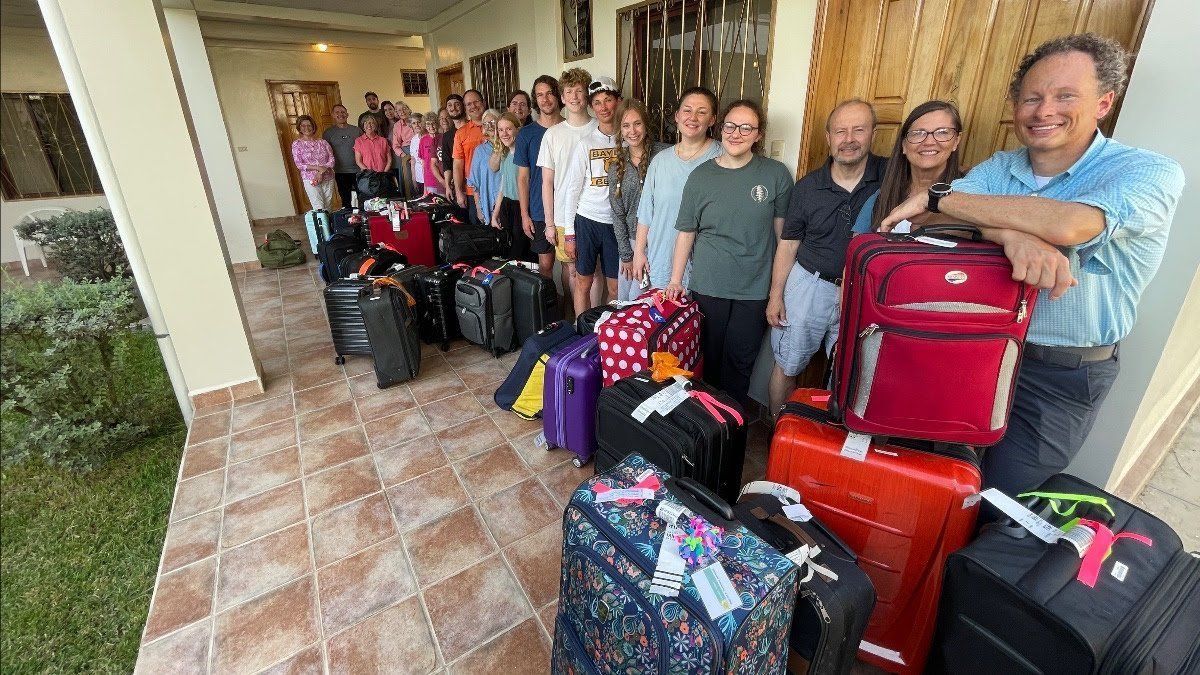 A group of people are standing in front of a bunch of luggage.