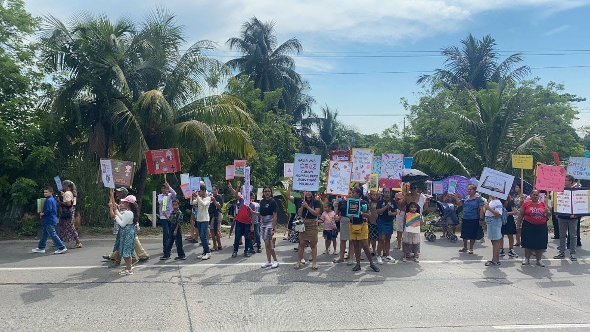 A group of people are standing on the side of the road holding signs.