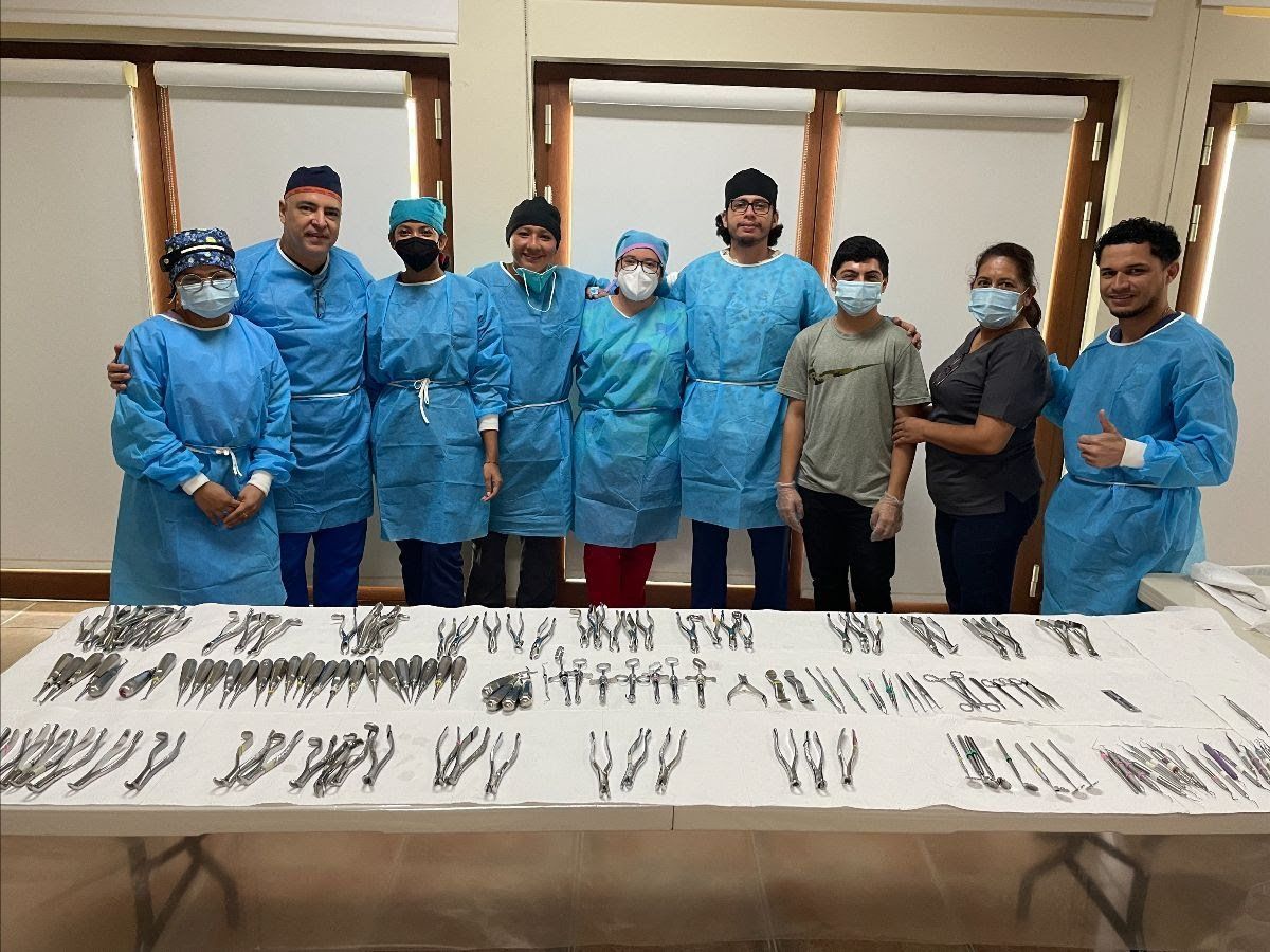 A group of doctors and nurses are posing for a picture in front of a table.