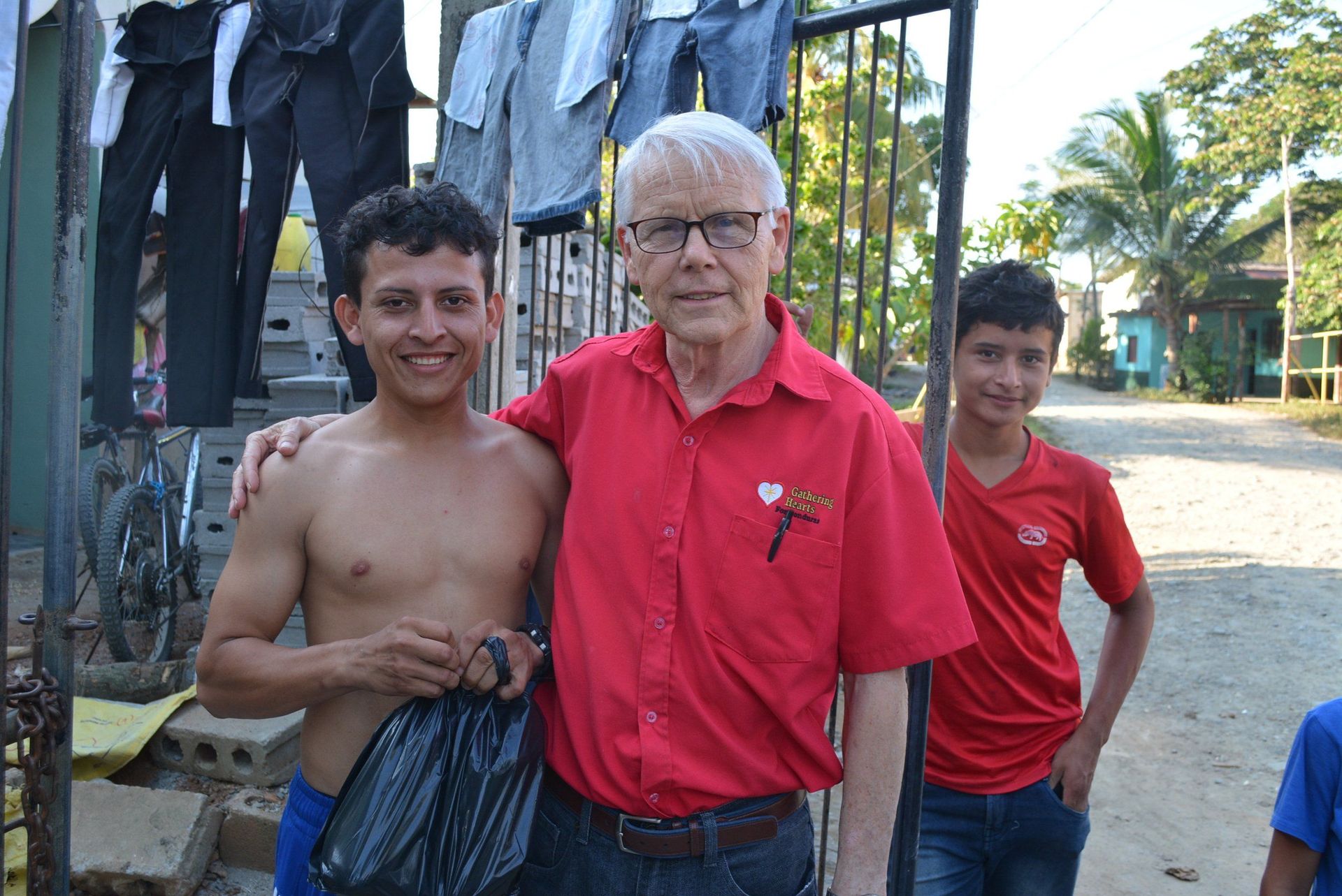 A man in a red shirt is posing for a picture with two boys.