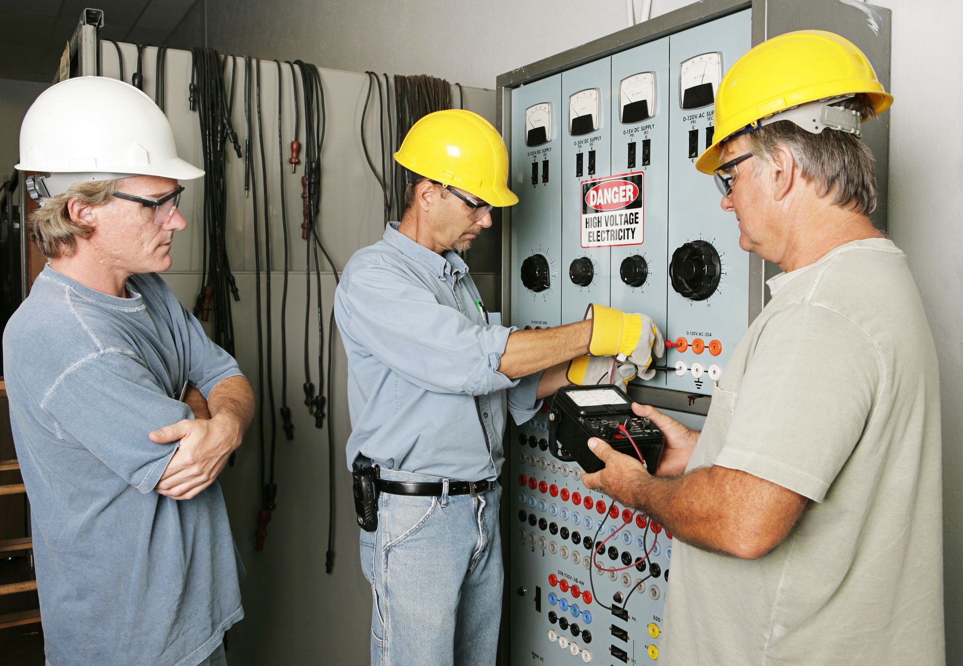 Industrial electricians inspecting a control panel.