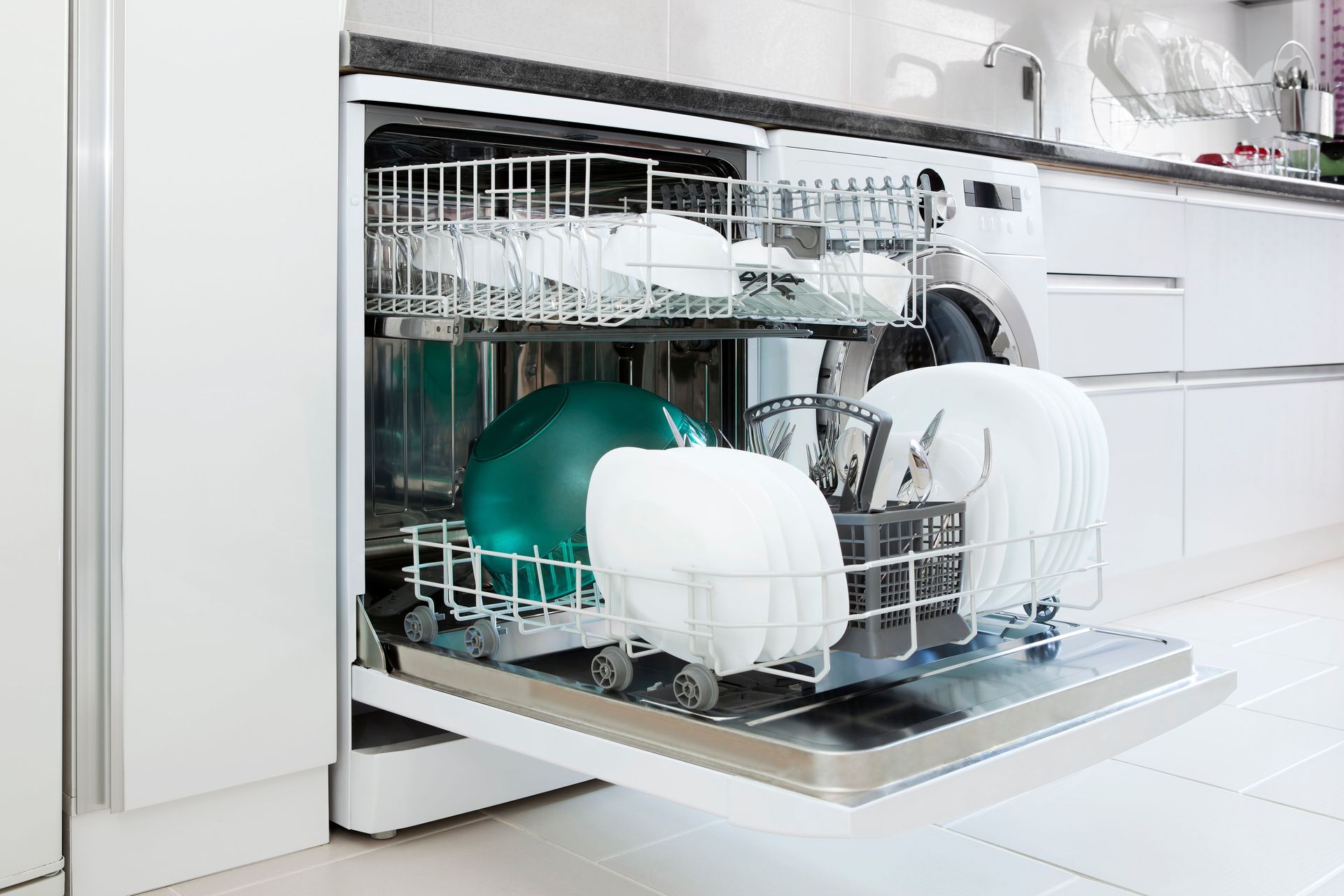 A dishwasher is filled with plates and bowls in a kitchen.
