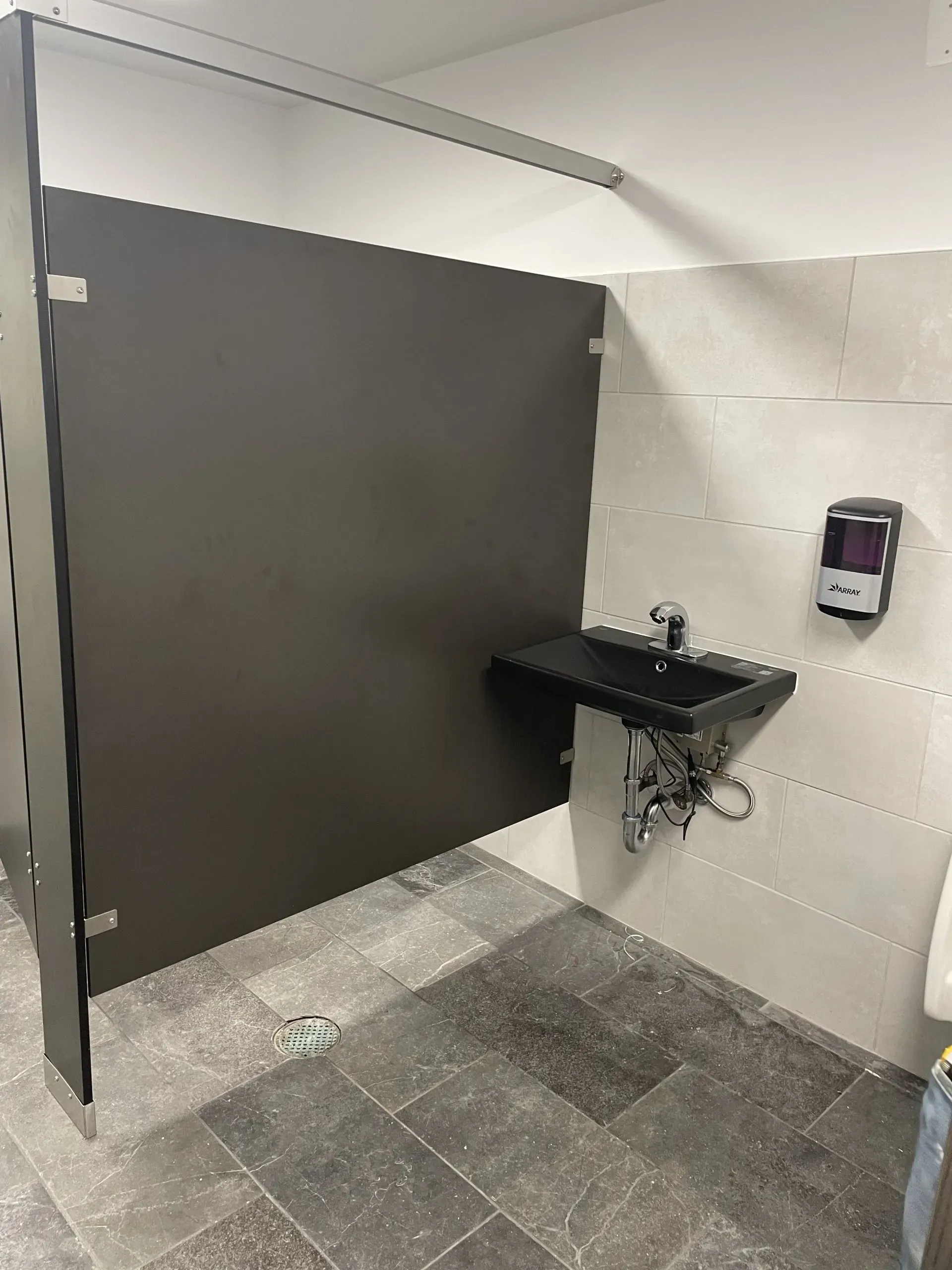 A bathroom with a sink and a soap dispenser on the wall.