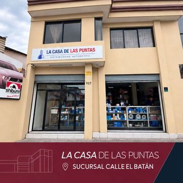 Storefront of “La Casa de las Puntas” in a beige building with glass windows and a sign for Calle El Batán.