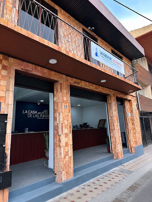 Exterior de una pequeña tienda de ladrillo con ventana de servicio abierta y un letrero sobre la entrada.