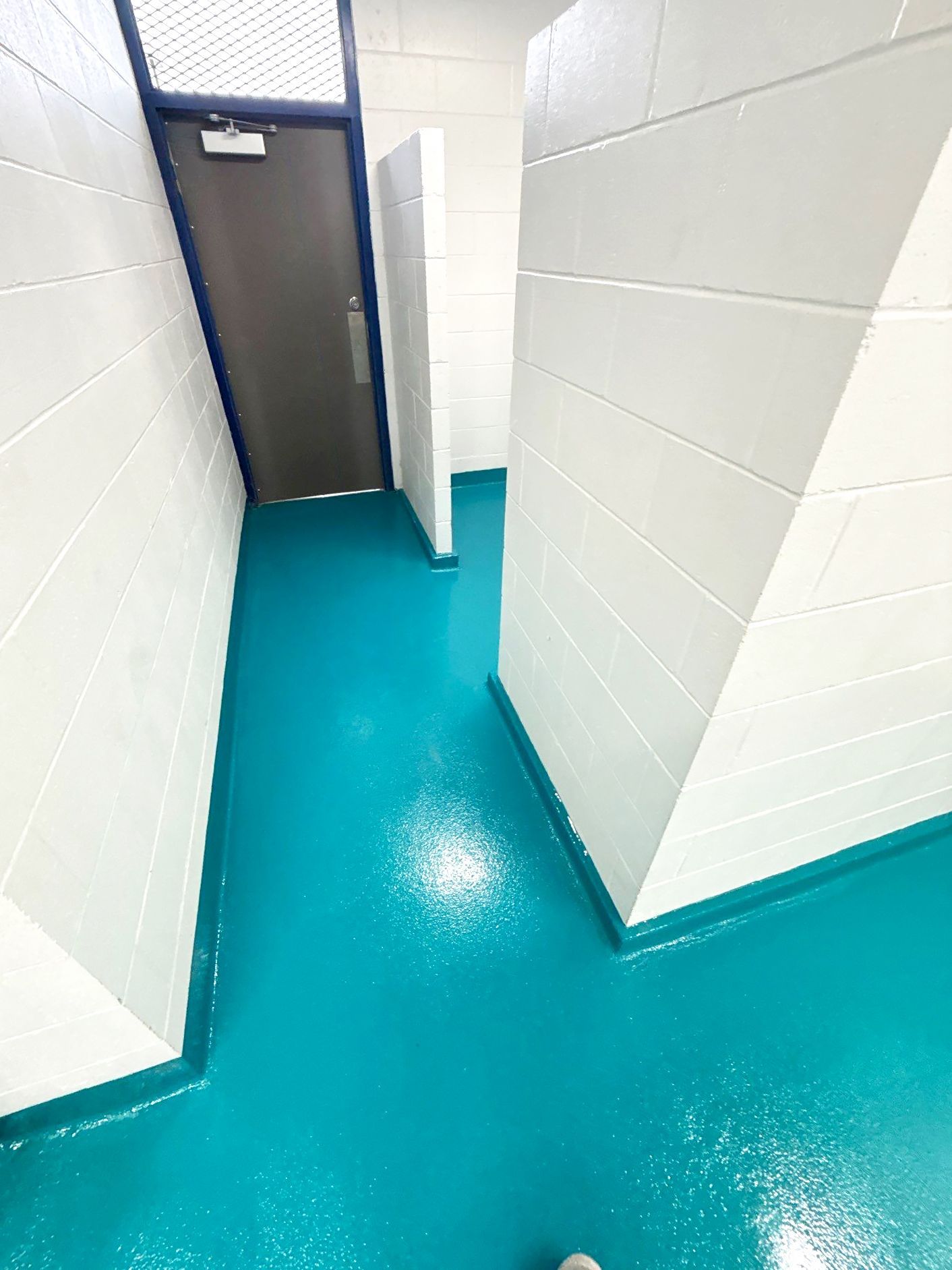 Solid-color epoxy floor in city pool interior rooms with full broadcast of 16/30 mesh sand for traction