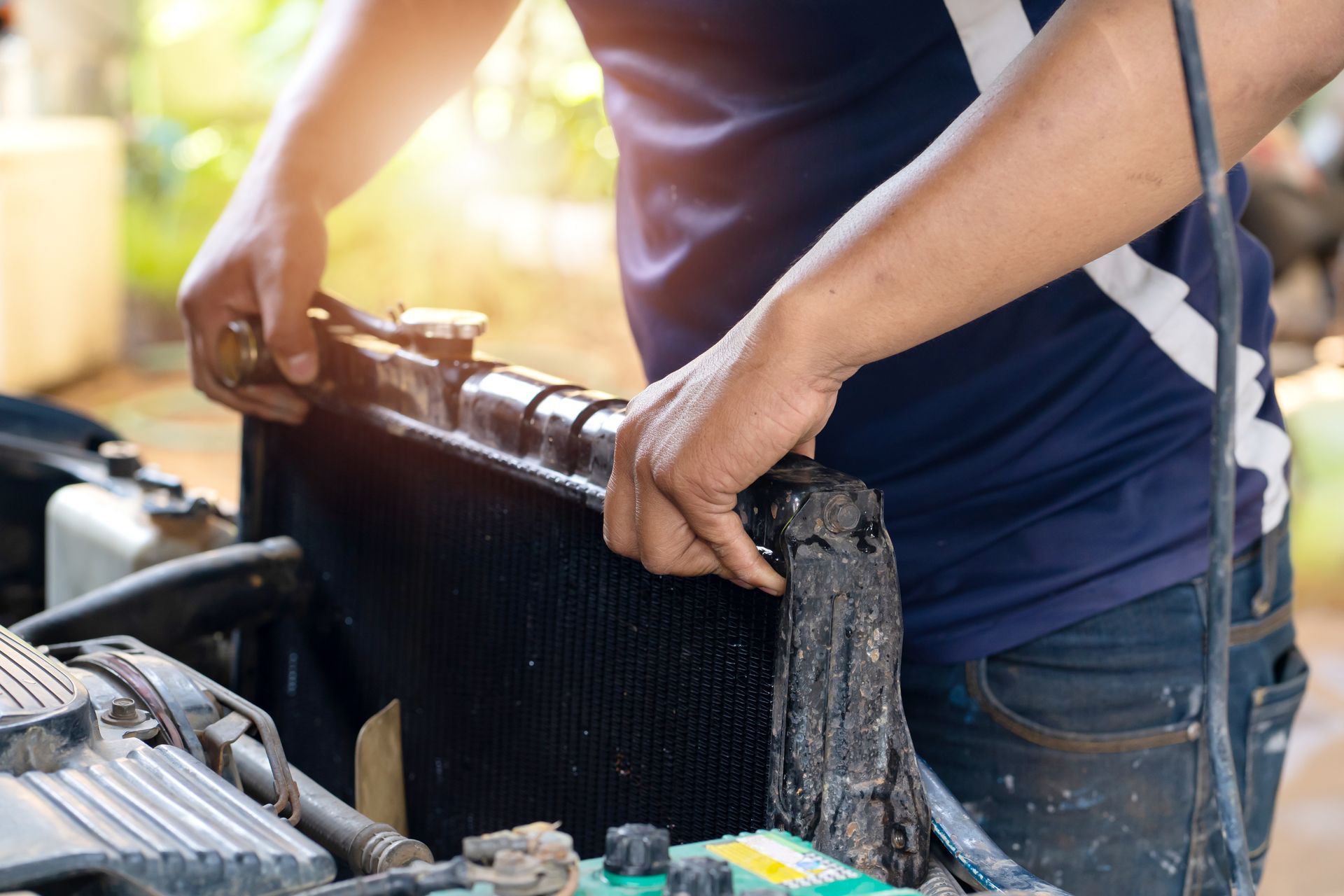 A man is fixing a radiator on a car with a wrench.