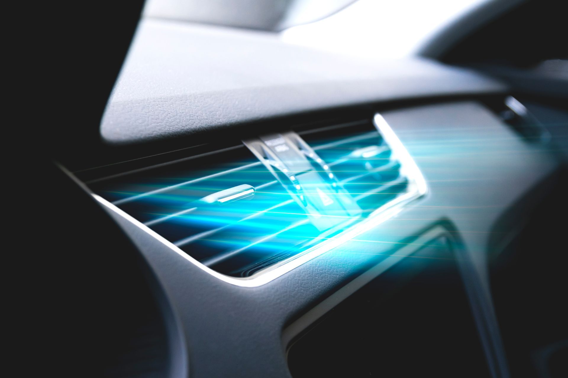 A close up of a car air vent with a blue light coming out of it.