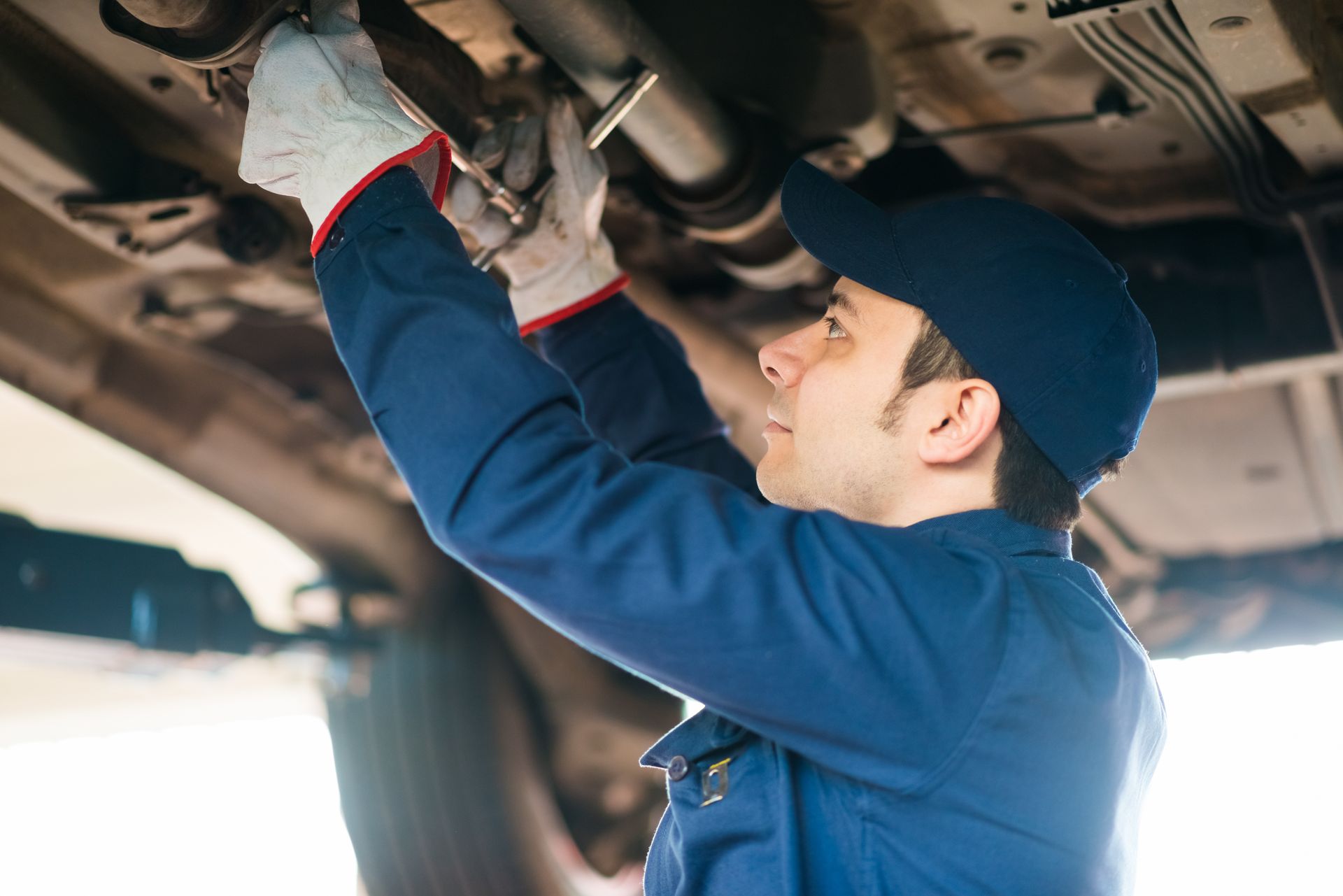 A man is working on the exhaust pipe of a car.