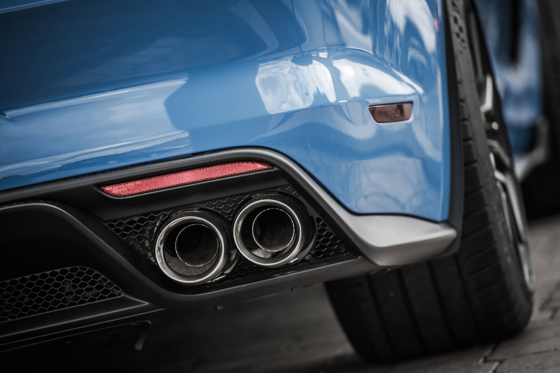 A close up of the exhaust pipes of a blue sports car.