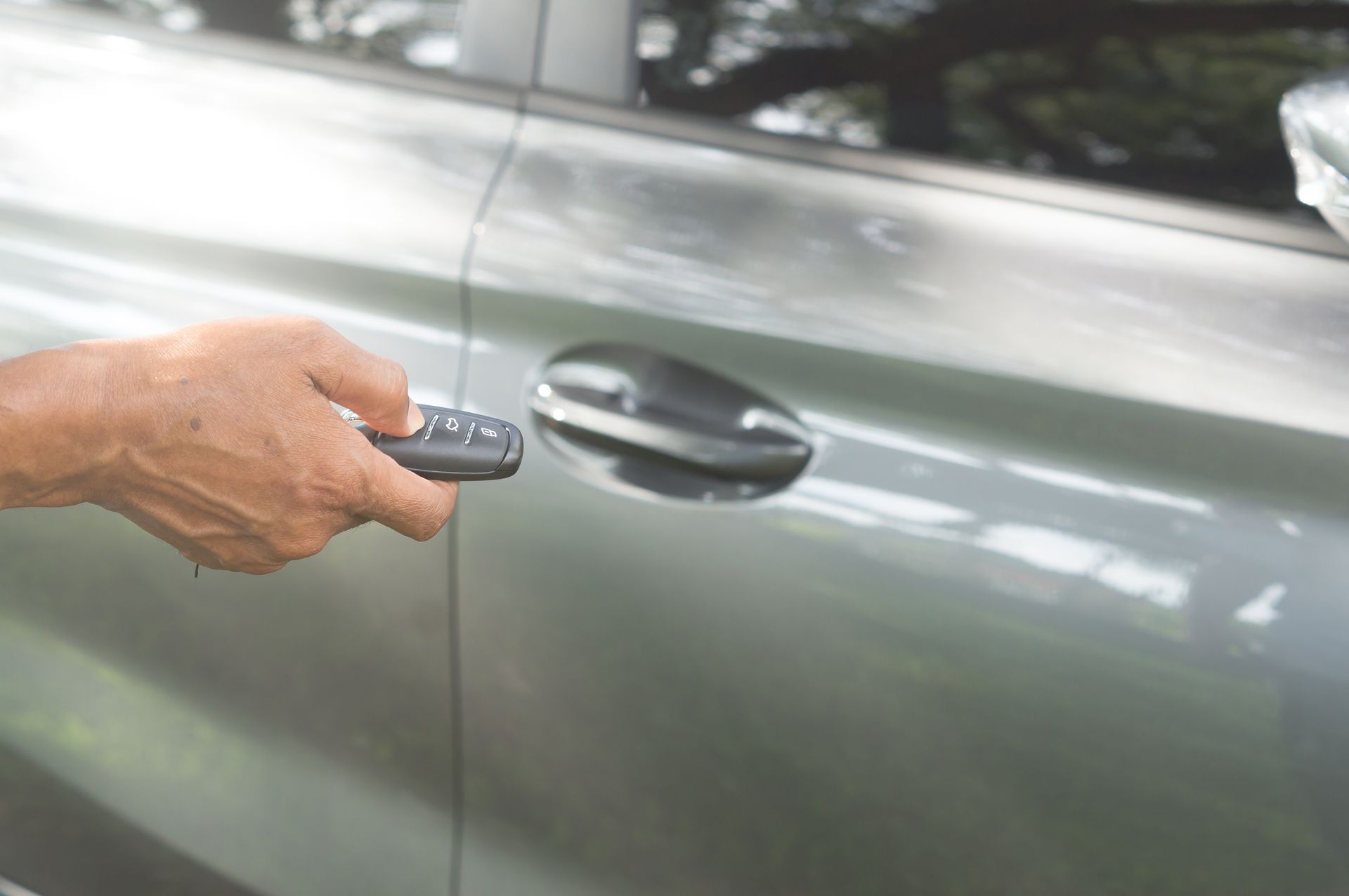 A person is using a remote control to open a car door.
