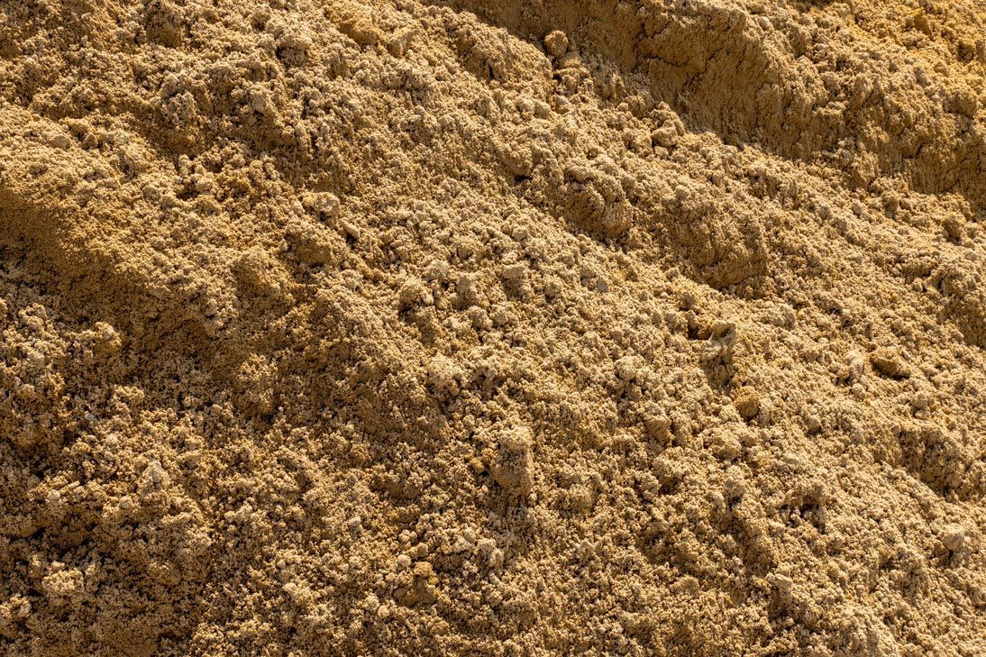 A pile of sand is sitting on top of a pile of dirt.
