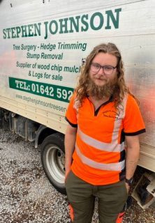 A man is standing in front of a stephen tree surgery truck.