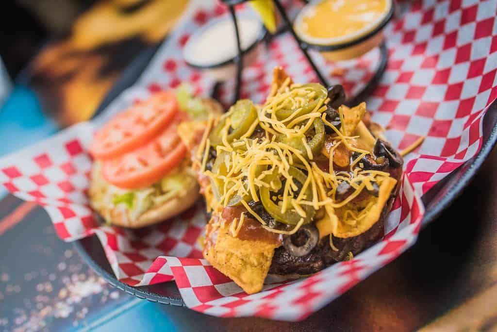 Two gourmet sliders with tomato and herbs on checkered paper trays