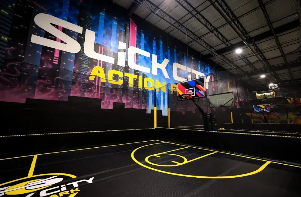 Indoor basketball court with large “Slick” action game sign and neon-style floor markings