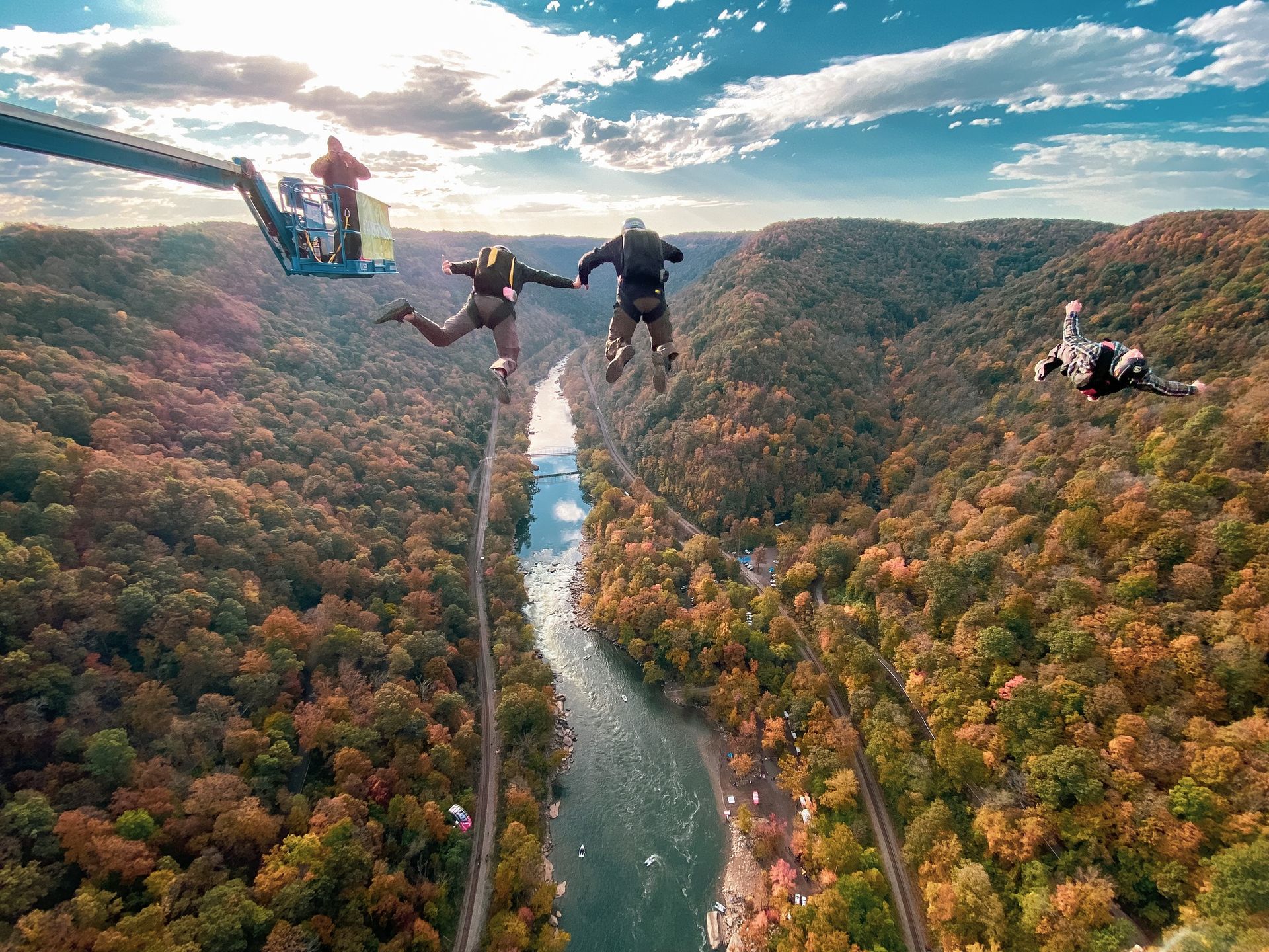 Paragliders soaring over a forested river valley at sunset