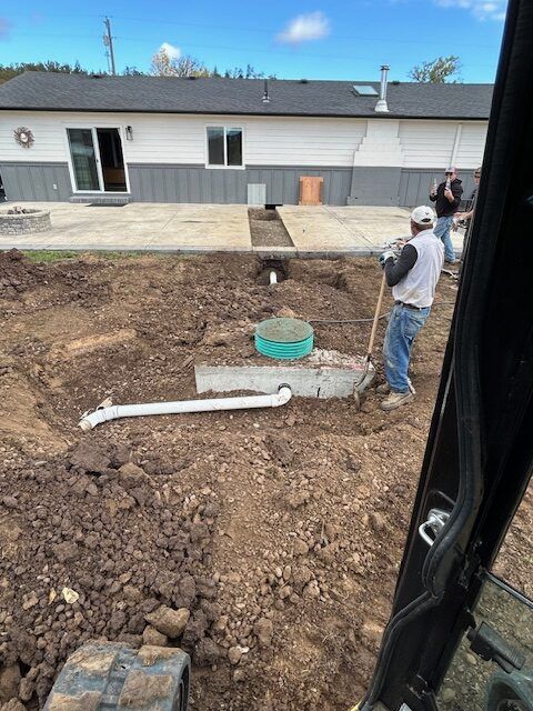A man is digging in the dirt in front of a house.