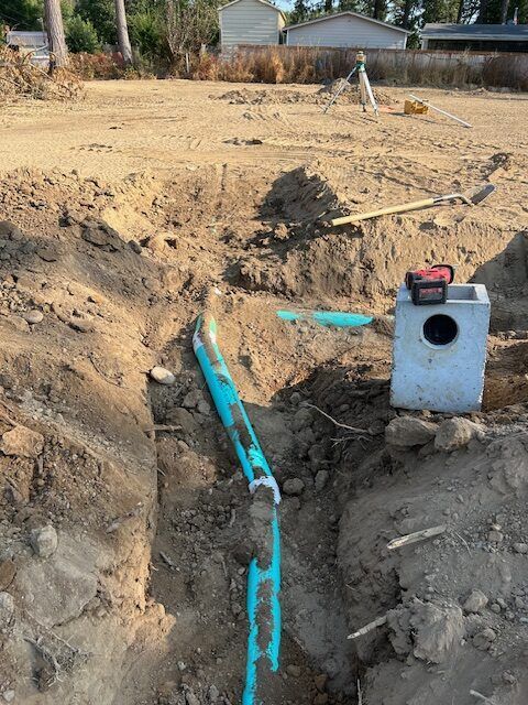 A blue pipe is sitting in the dirt next to a concrete block.