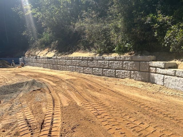 A large stone wall is being built on the side of a dirt road.