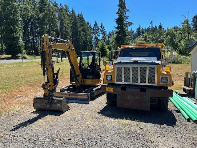 An excavator and a truck are parked next to each other on a dirt road.