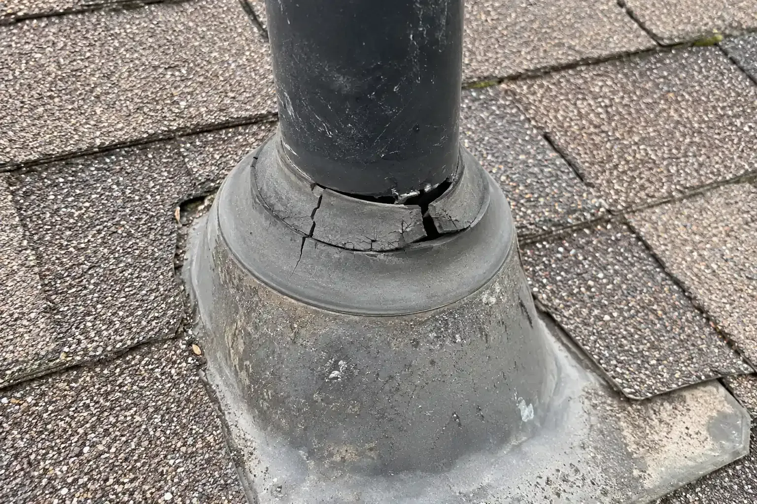 Hardened, split rubber boot around a plumbing vent pipe