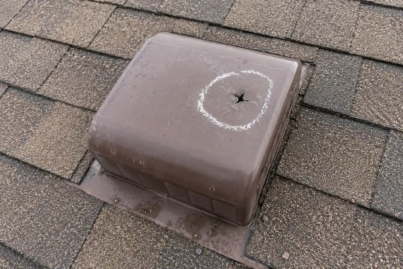 Plastic box vent on a shingle roof with a jagged hail crack