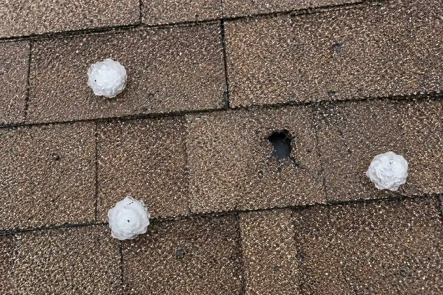 Large hailstone and a broken shingle, tape measure for scale