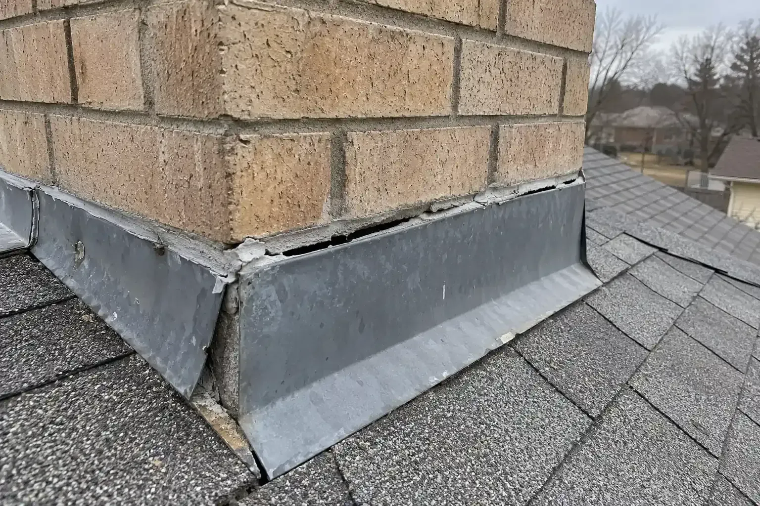 Gap between chimney flashing and brick where the seal has failed