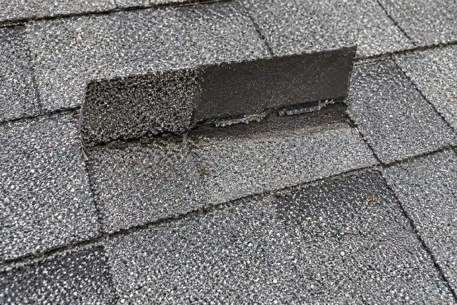 Creased shingle folded back by wind, with a broken seal