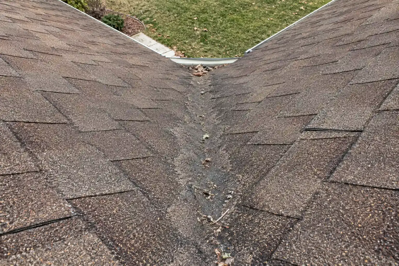 Worn, thinning shingles along the valley where two roof slopes meet