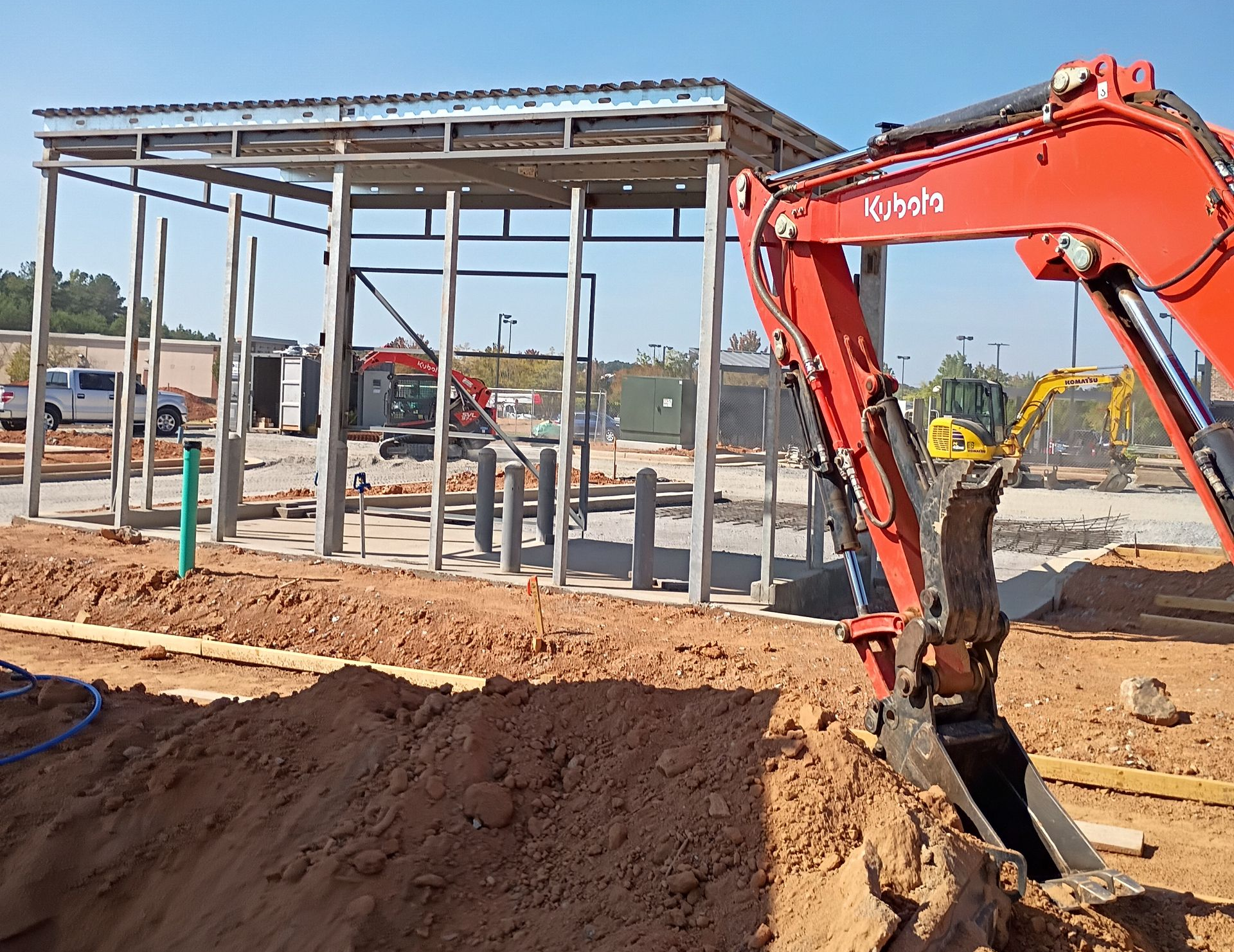 Orange excavator at a construction site beside a steel-framed building under construction