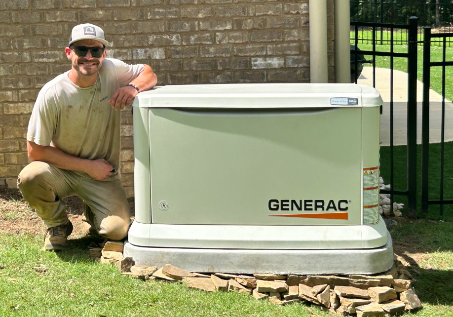 White industrial generator unit beside a brick building on a concrete pad outdoors