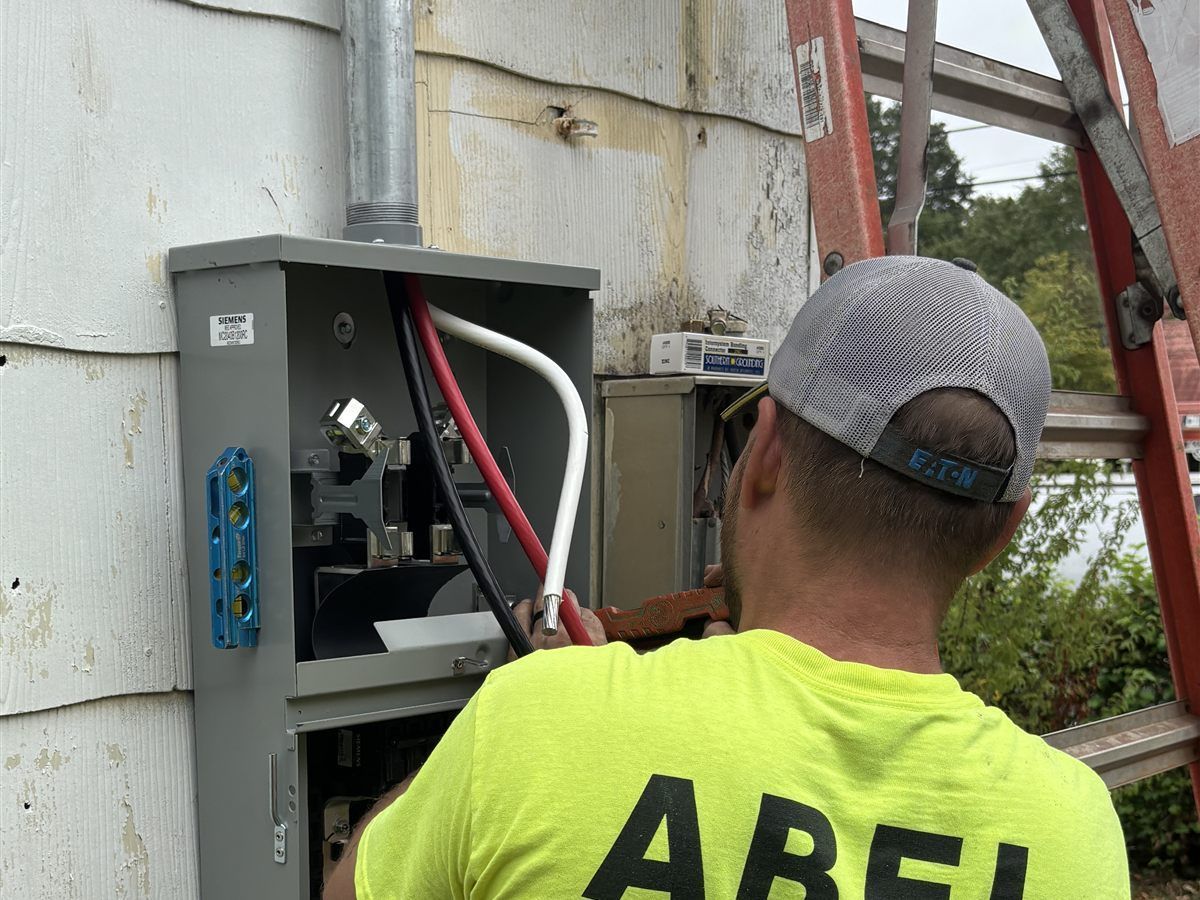 Electricista de Abel Electric trabajando en el panel eléctrico de una casa