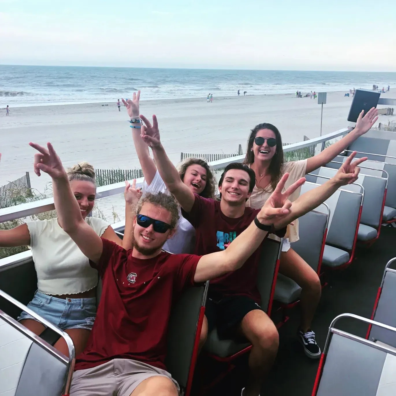 A group of people are sitting on a bus with their arms in the air.