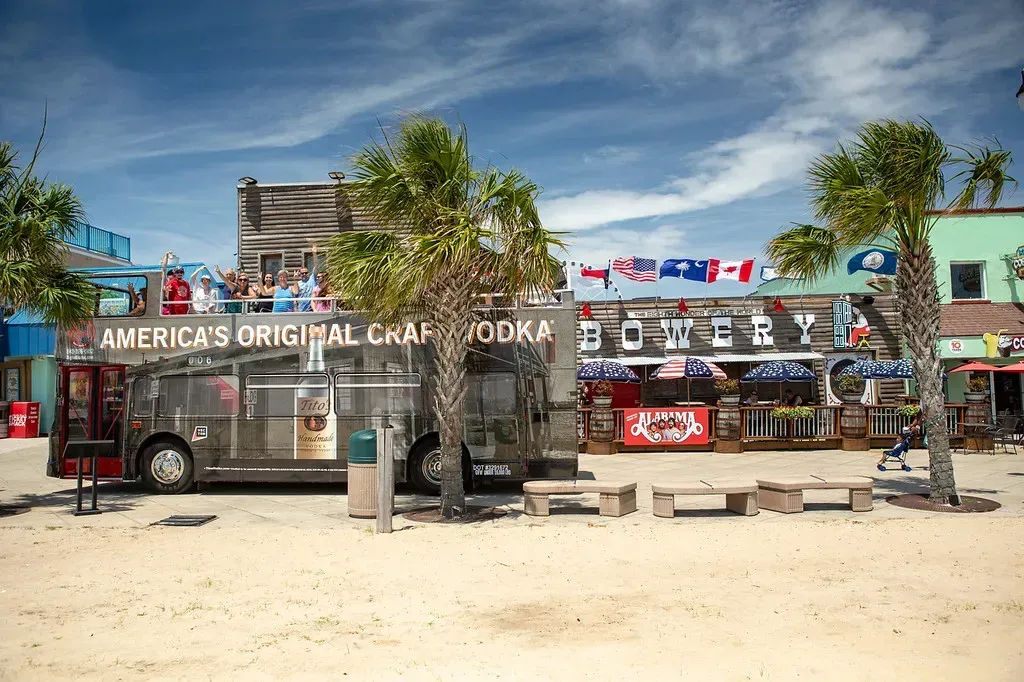 A bus is parked on the beach in front of a restaurant.