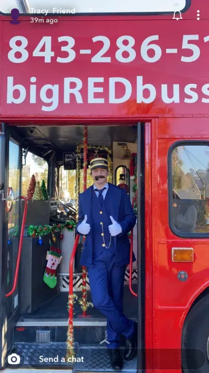 A man in a suit is standing in front of a red bus that says big red bus