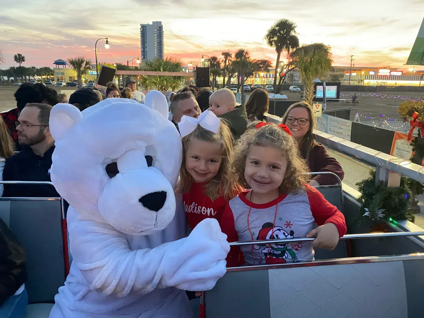 A polar bear mascot is standing next to two little girls on a boat.