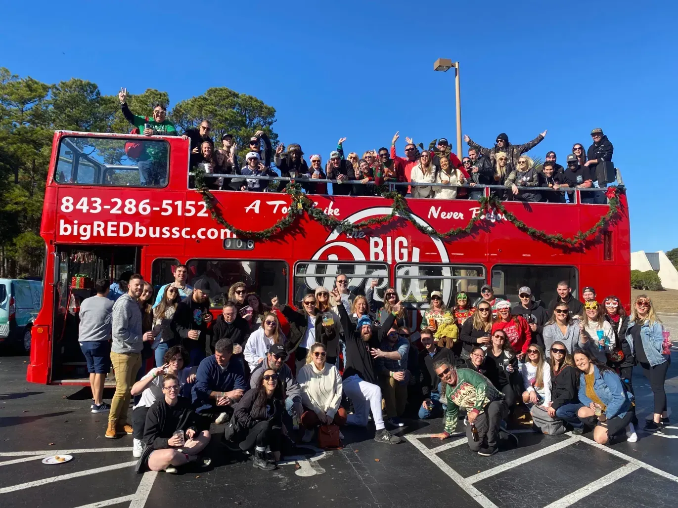 A group of people are posing for a picture in front of a big red bus