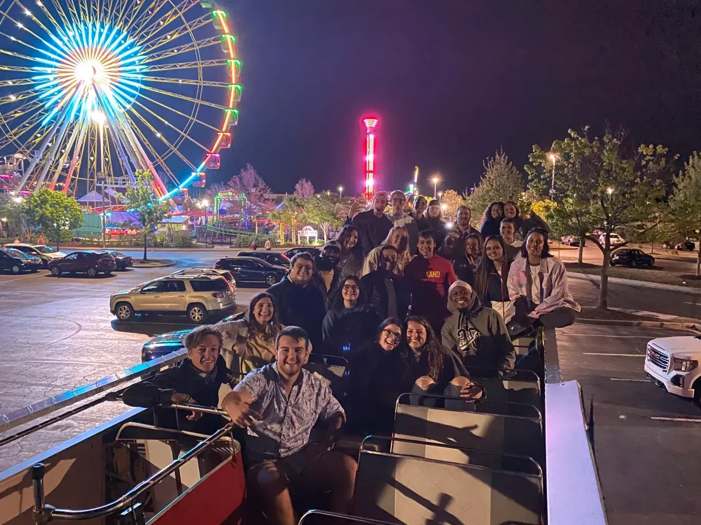 A group of people are posing for a picture in front of a ferris wheel.