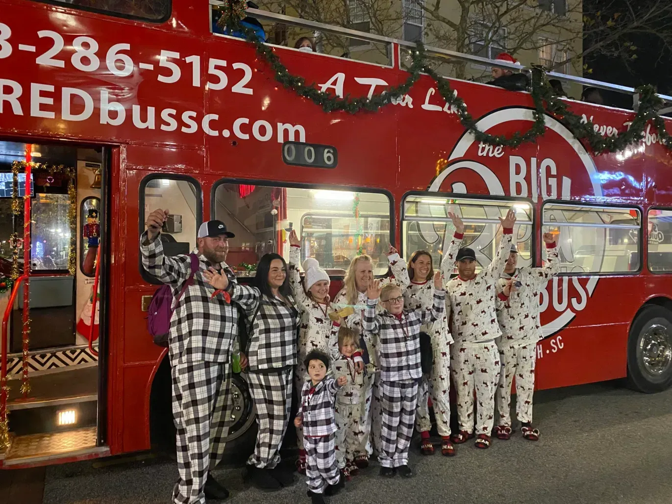 A group of people in pajamas are standing in front of a red bus.