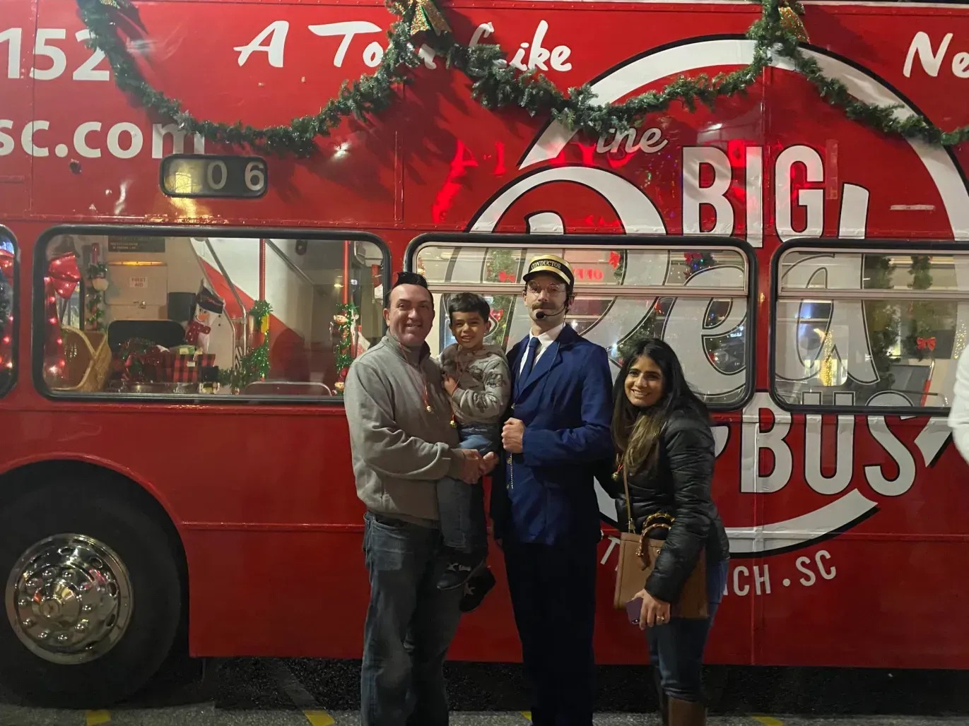 A group of people standing in front of a red bus that says the big bus