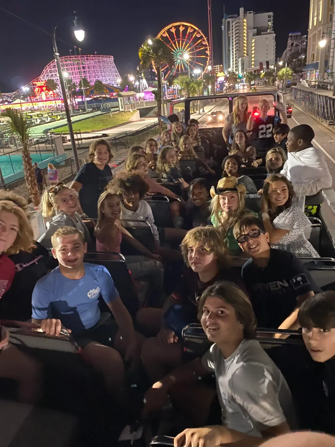 A group of people are riding a roller coaster at night.