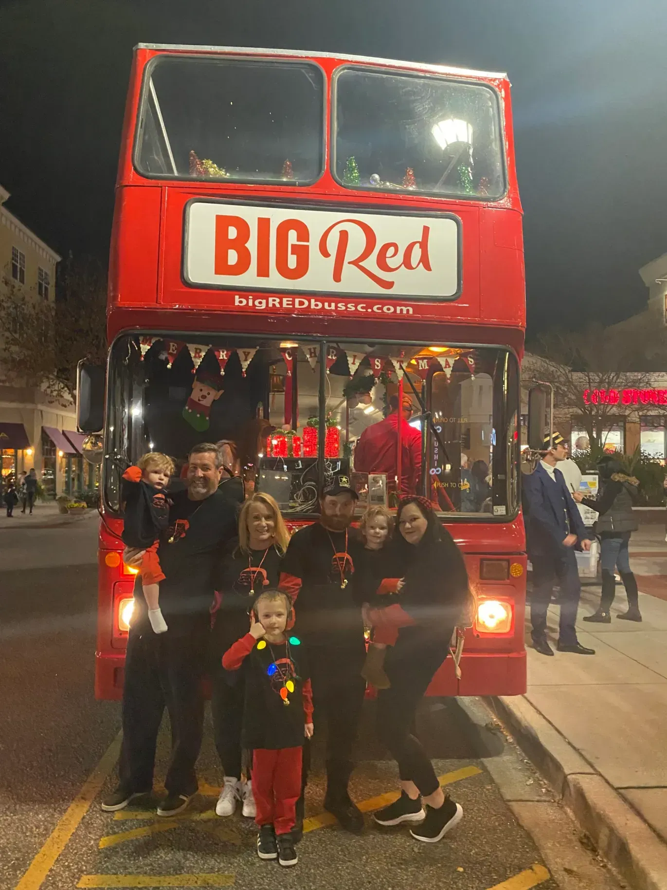 A group of people standing in front of a big red bus