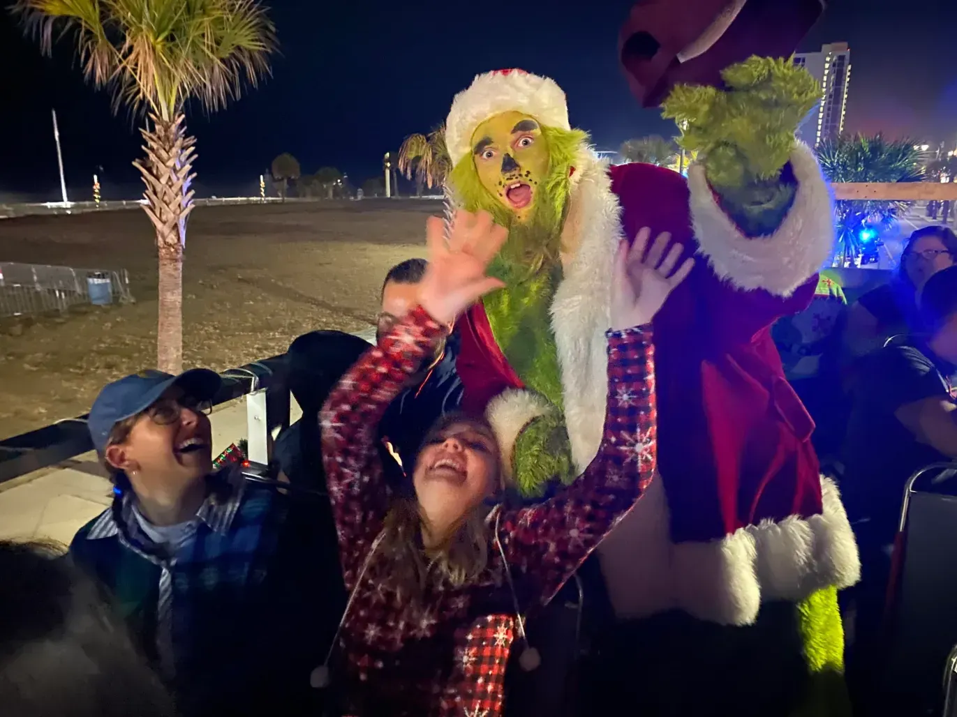 A group of people are standing next to a grinch statue.