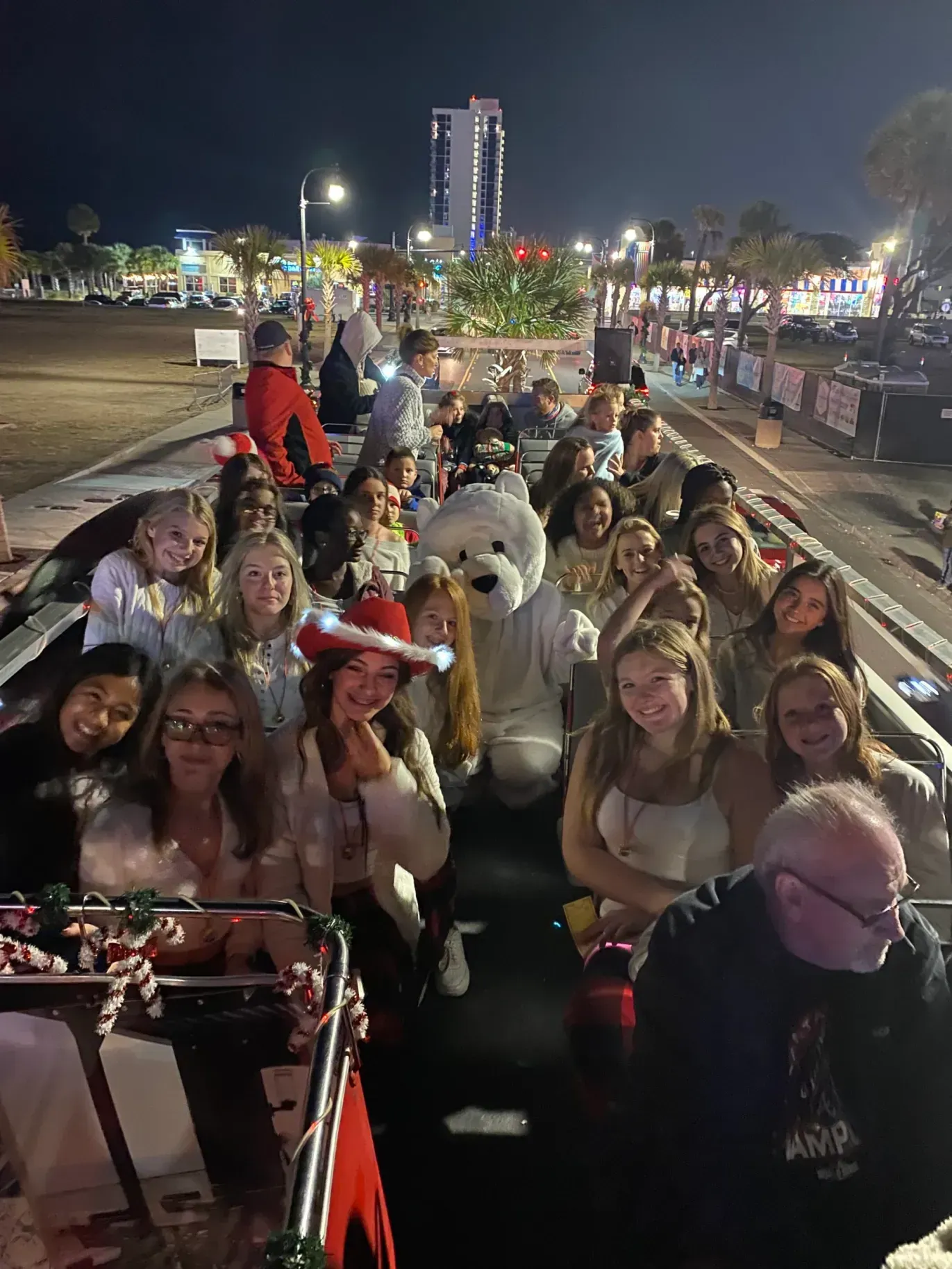 A group of people are sitting in a sleigh with a teddy bear.