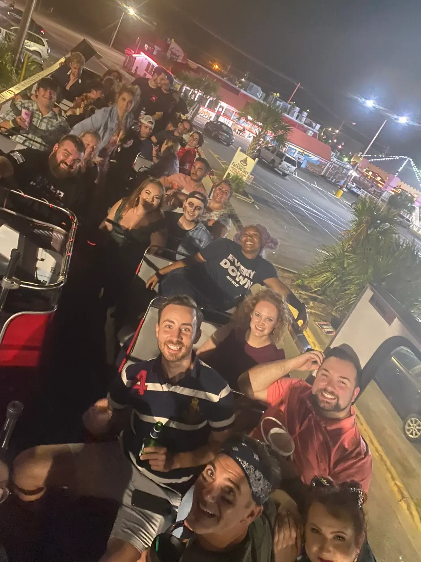 A group of people are posing for a picture in a parking lot at night.