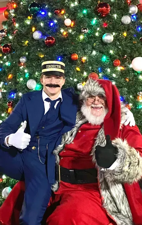 A man dressed as a police officer and santa claus are posing for a picture in front of a christmas tree.