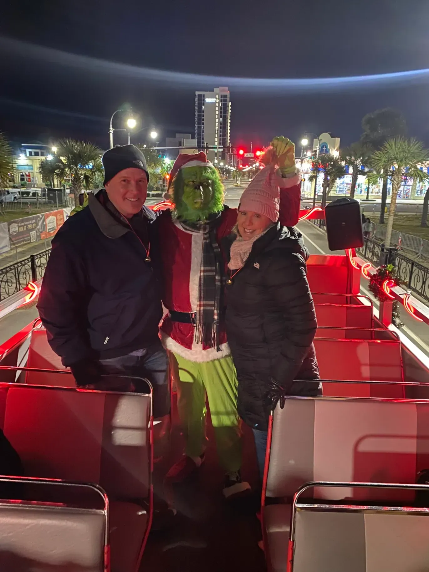 A man and a woman are standing next to a grinch on a boat.