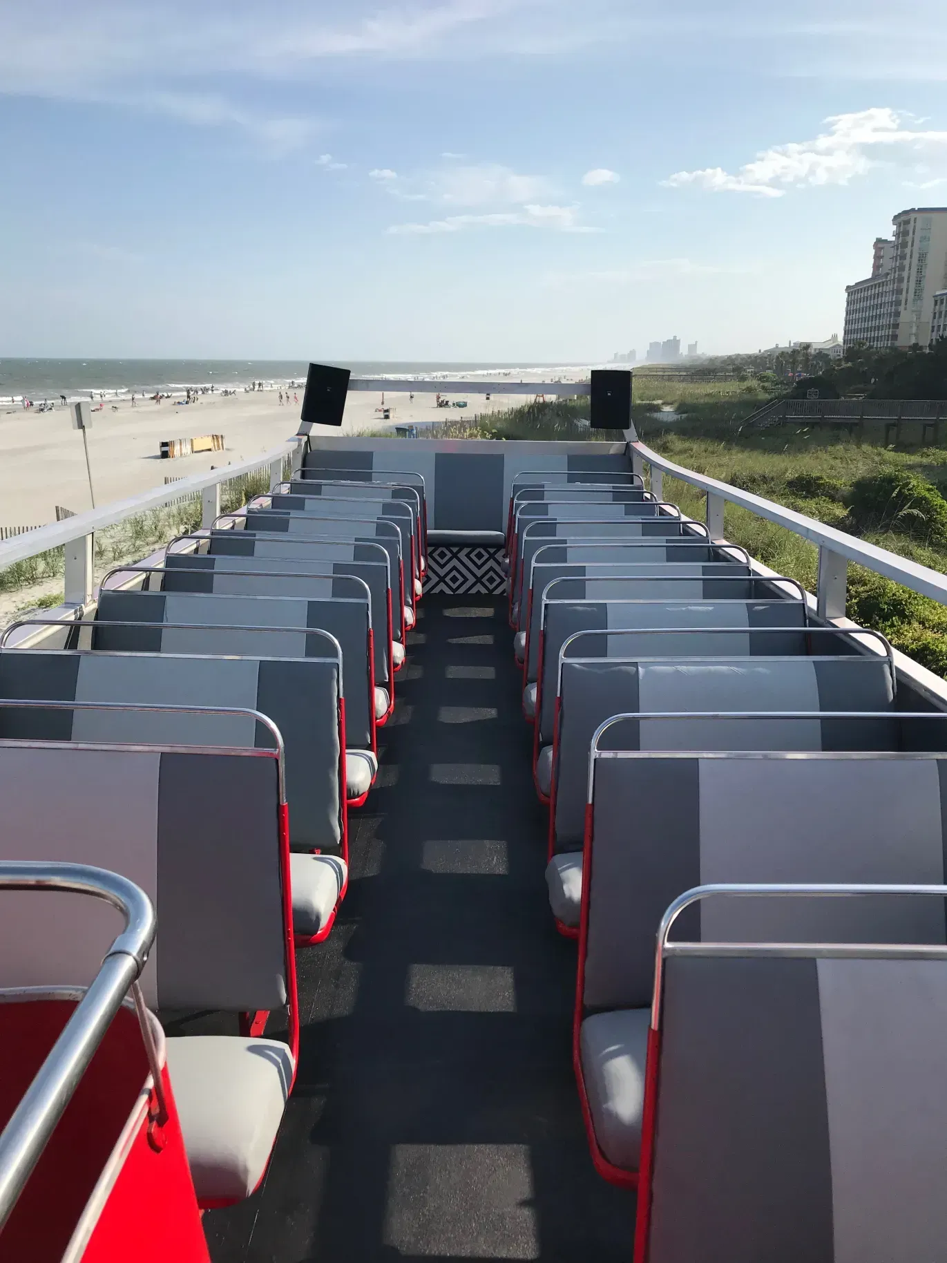 The inside of a double decker bus with a view of the beach.
