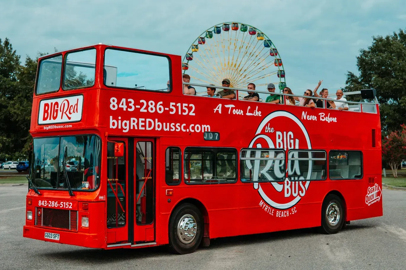 A red double decker bus with a ferris wheel in the background